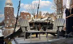 A chair and table set on a platform with a clock tower in the background.