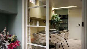 Un coin repas avec une table ronde et des chaises, une plante en pot et une vue sur la cuisine.