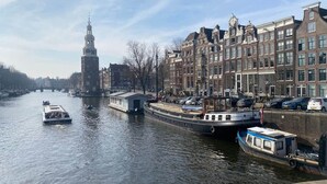 Un canal con barcos, edificios históricos y una torre destacada.