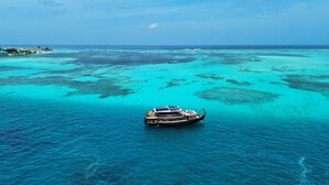 A boat with a deck and a cabin, floating on turquoise waters with clear skies. - Atoll Villa (Hulhumalé)