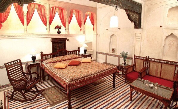 A traditional room with a large bed, wooden furniture, and red curtains. - Hotel Mandawa haveli (Mandawa)