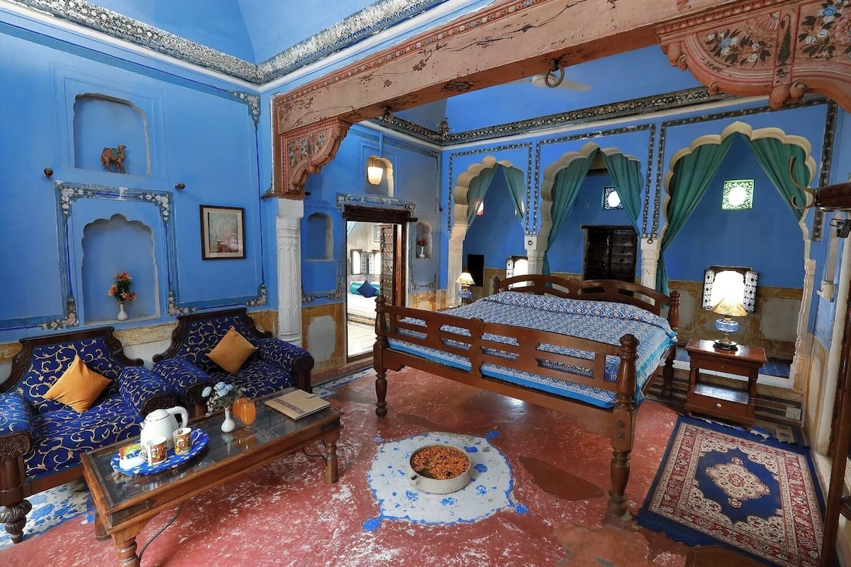 A traditional room with a bed, sofa, and a small table with a teapot and cups.