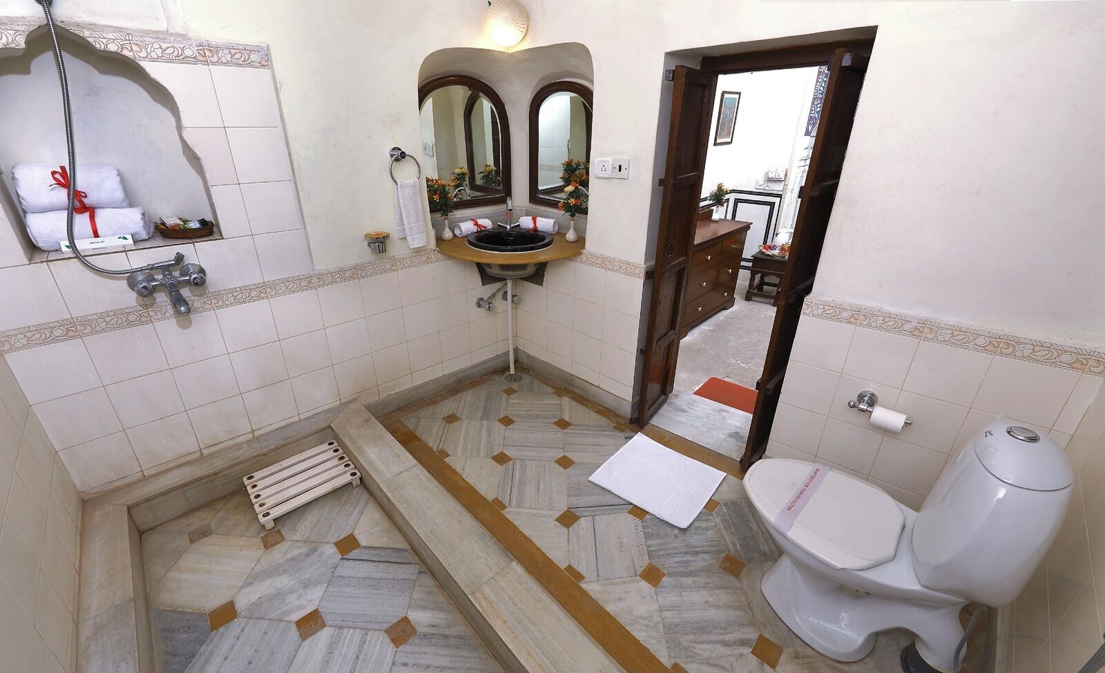 Un baño con lavamanos, espejo, inodoro, ducha y suelo de baldosas.