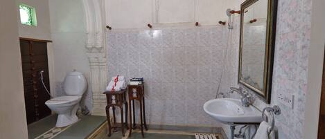 A bathroom with a toilet, sink, and mirror. There are two wooden stools with towels.