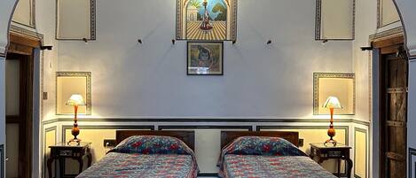 Ein Zimmer mit zwei hölzernen Betten, einer Chandelieber und einem gerahmten Bild an der Wand.