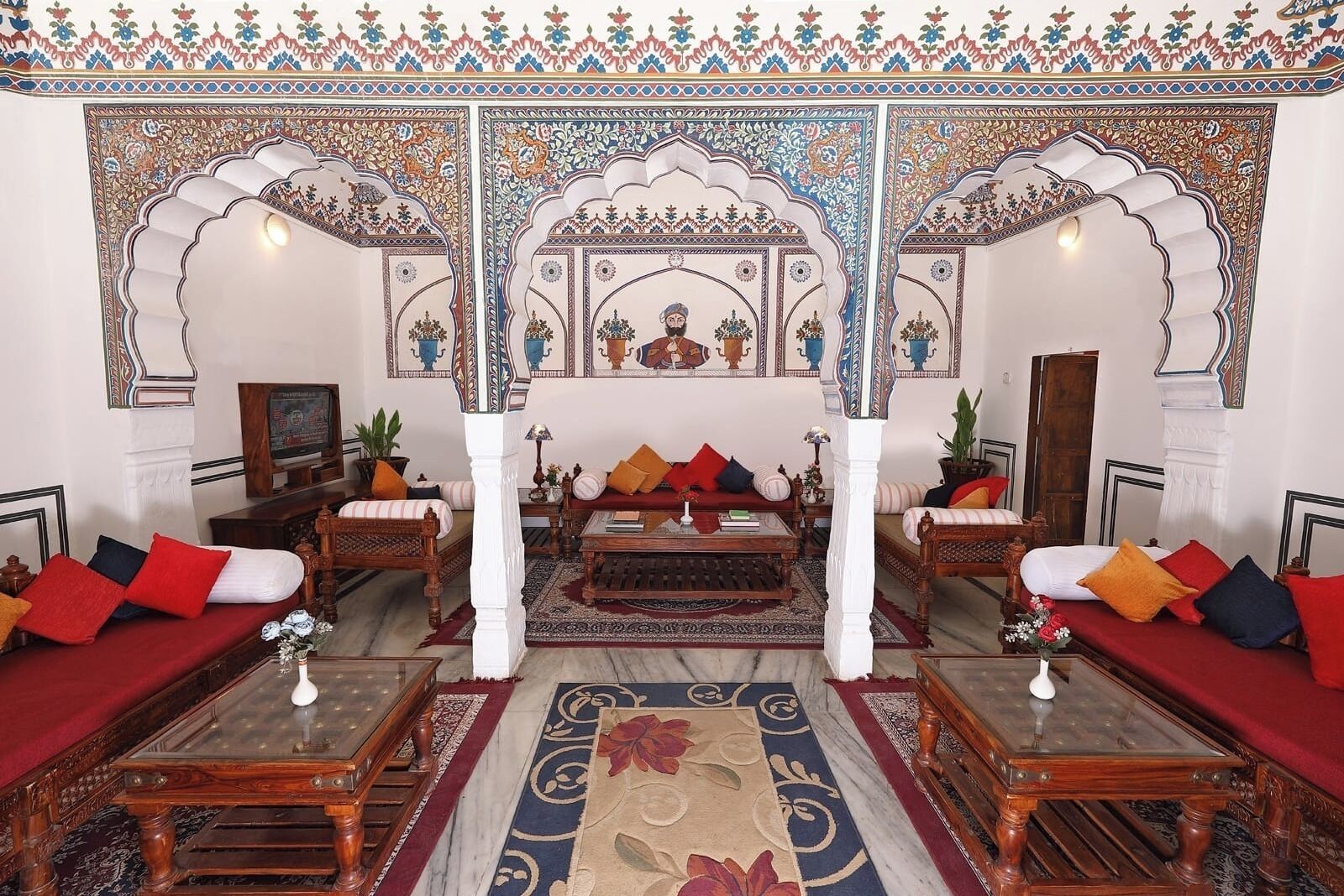 A traditional interior with ornate arches, a central sofa set, and a patterned rug.