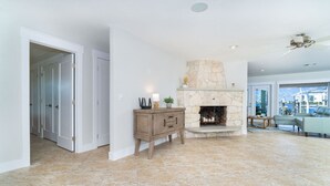 A living room with a stone fireplace, a wooden cabinet, and a view of the outside.