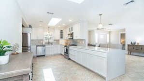 A modern kitchen with white cabinetry, a central island, and a skylight.