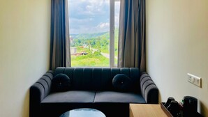 A small room with a sofa, a table, and a window with curtains. - Dhairya Garh  (Udaipur)