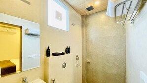 A modern bathroom with a bathtub, a shower, and a toilet. There is a mirror above the sink, and toiletries are placed on the wall. - Dhairya Garh  (Udaipur)