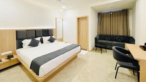 A modern hotel room with a large bed, a desk, a sofa, and a separate bathroom. - Dhairya Garh  (Udaipur)