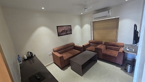 Una sala de estar moderna con un sofá modular, una mesa de centro, un televisor y un equipo de aire acondicionado.