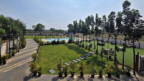 Un área de piscina con cielo despejado, césped bien cuidado y mobiliario exterior.