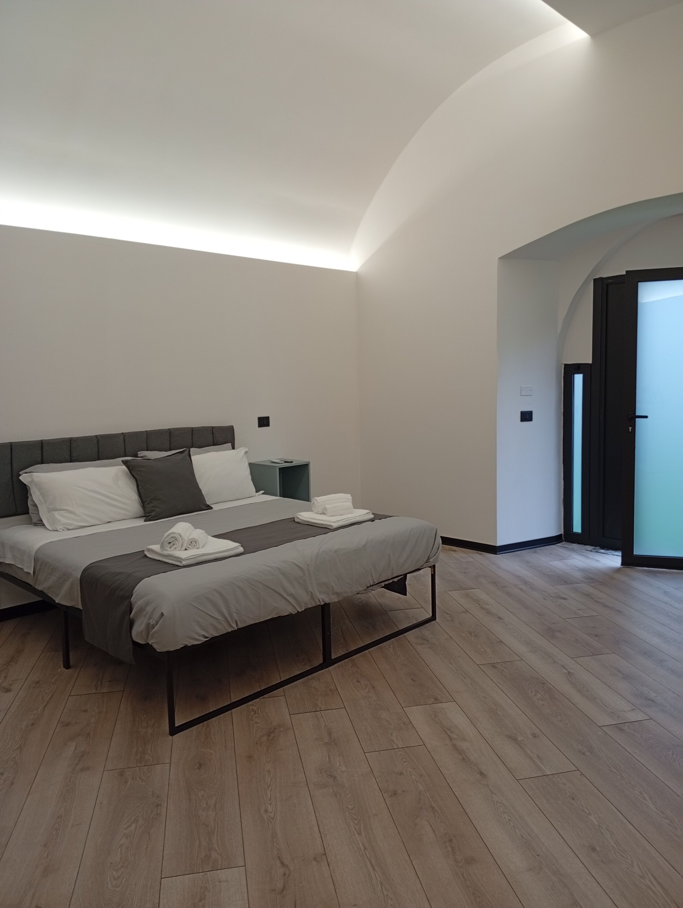 A modern bedroom with a bed, bedside tables, and a wooden floor.