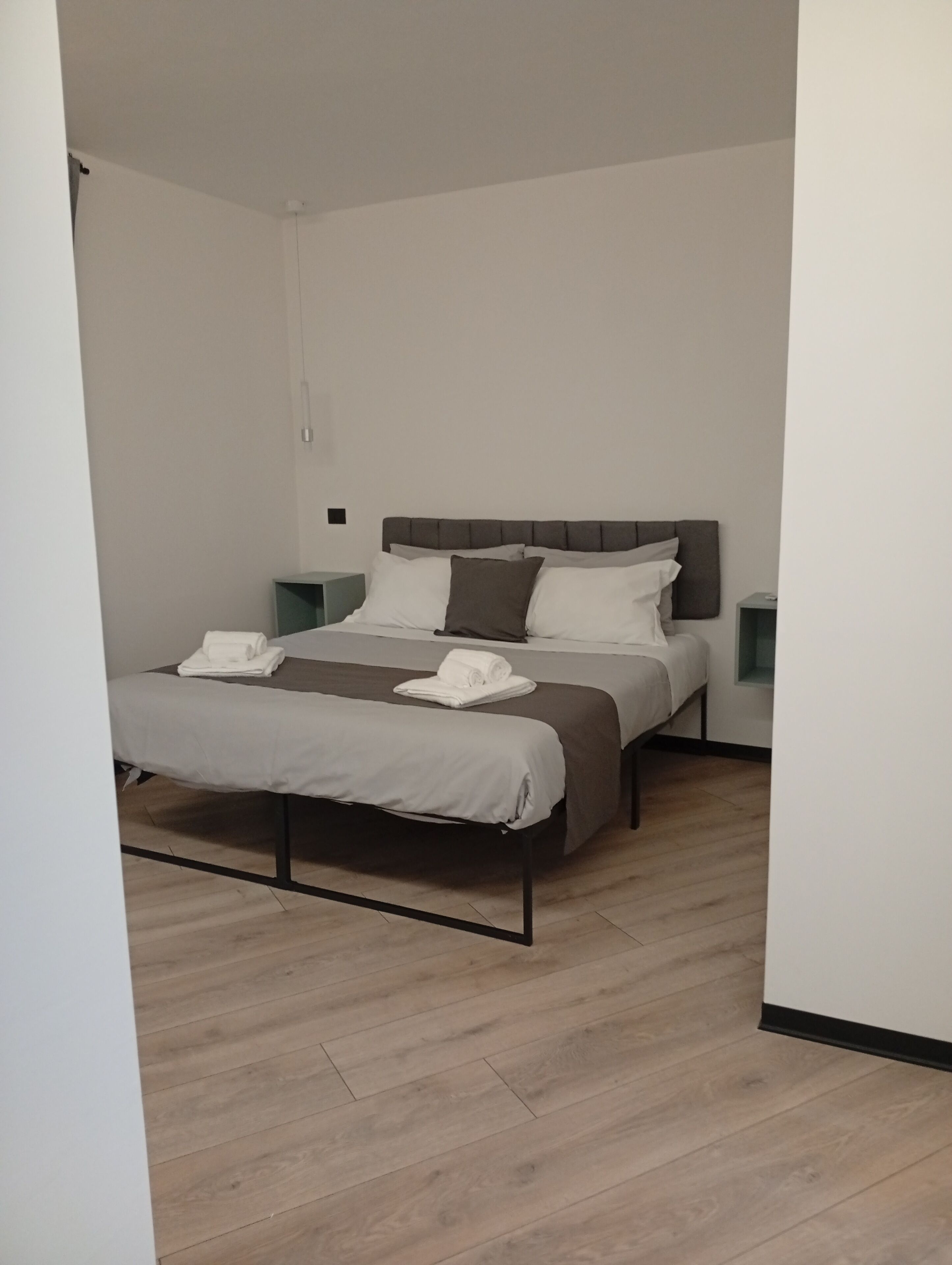 A modern bedroom with a double bed, a bedside table, and a nightstand.