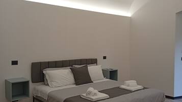A modern bedroom with a bed, bedside tables, and a wooden floor.