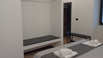 Ein modernes Hotelzimmer mit einem großen Bett, einem flachbildfernseher an der Wand, einer Sitzbank und einem Spiegel.