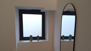 Um quarto com janela, espelho e radiador.