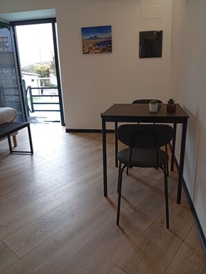 A room with a wooden floor, a dining table with two chairs, a small potted plant, and a wall-mounted picture. - Borgo Double V (Napoli)