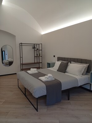 Una camera da letto moderna con un letto, un comodino, uno specchio e un'unità contenitore.