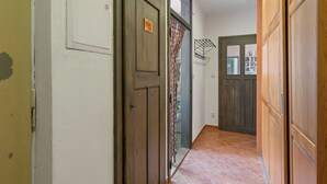 A hallway with wooden doors, a tiled floor, and a white wall with a doorbell. - Relax na Šumavě by Interhome (Kasperske Hory)