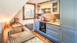 A modern kitchen with a built-in oven, a sink with a strainer, and a window with a view of the outdoors. - Pine Needle Lodge by Interhome (Invergarry)