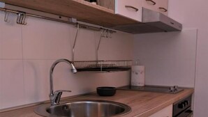 A modern kitchen with a stainless steel sink, wooden countertop, and a built-in oven. - One Bedroom Apartment with Terrace & Garden View (Supetar)