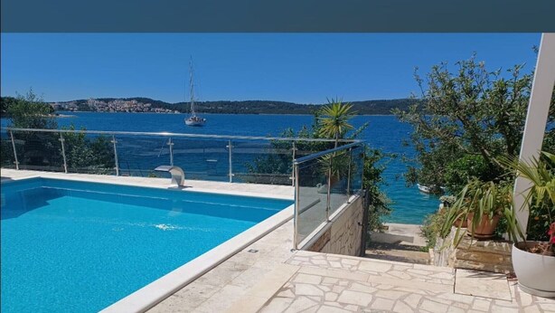 A swimming pool with a clear view of the sea and a sailboat in the distance. - Two-bedroom Apartment With Sea View (A1) (Trogir)