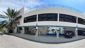 Um edifício moderno com fachada curva, grandes janelas e área de estacionamento coberta.