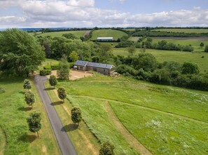 A rural property with a house, a driveway, and surrounding fields.