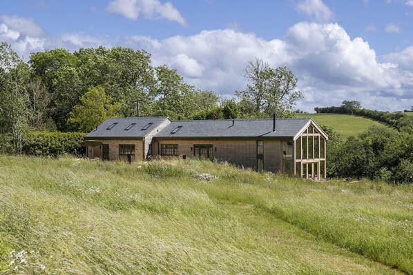 A rustic stone building with a sloped roof, large windows, and a glass extension.