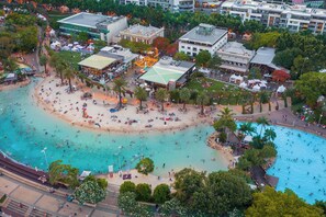 Luftaufnahme eines Küstenresorts mit Strand, Schwimmbecken und mehreren Gebäuden.