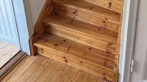 Een houten trap met witte muren en een houten leuning.