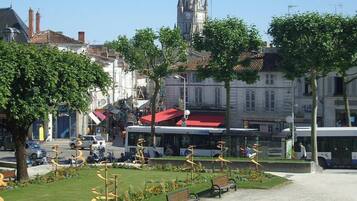 A city square with a central fountain, benches, and a bus stop.