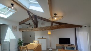 A spacious living area with a wooden dining table, a TV, and a ceiling fan.