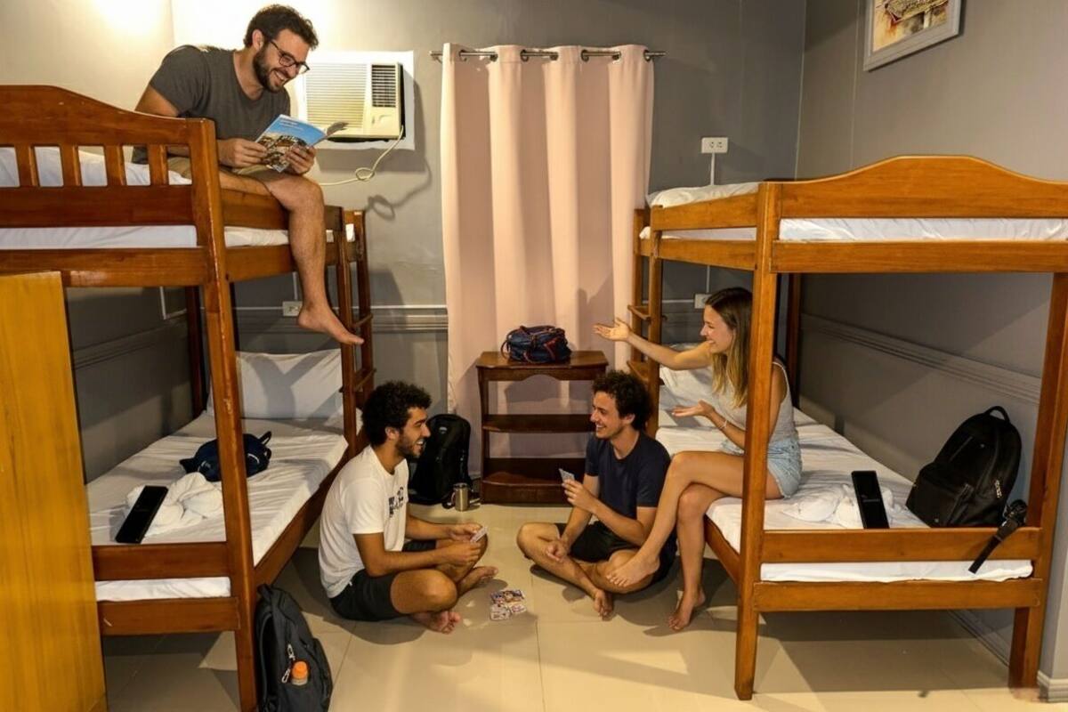Une chambre de dortoir avec des lits superposés, une petite table et une fenêtre avec des rideaux.