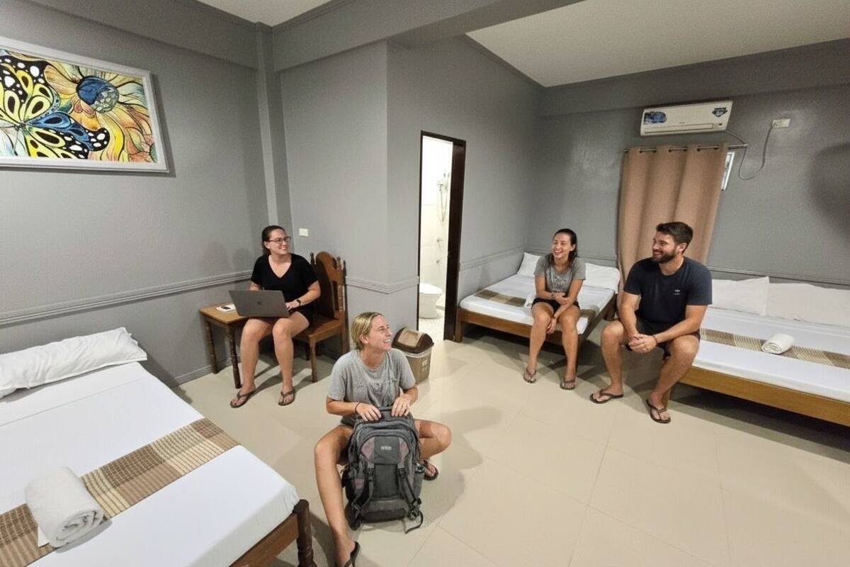 Une chambre avec quatre lits, un tableau au mur et un appareil de climatisation.