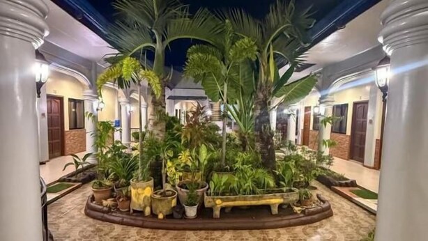 Un patio central con jardín, rodeado de columnas y suelo de baldosas.