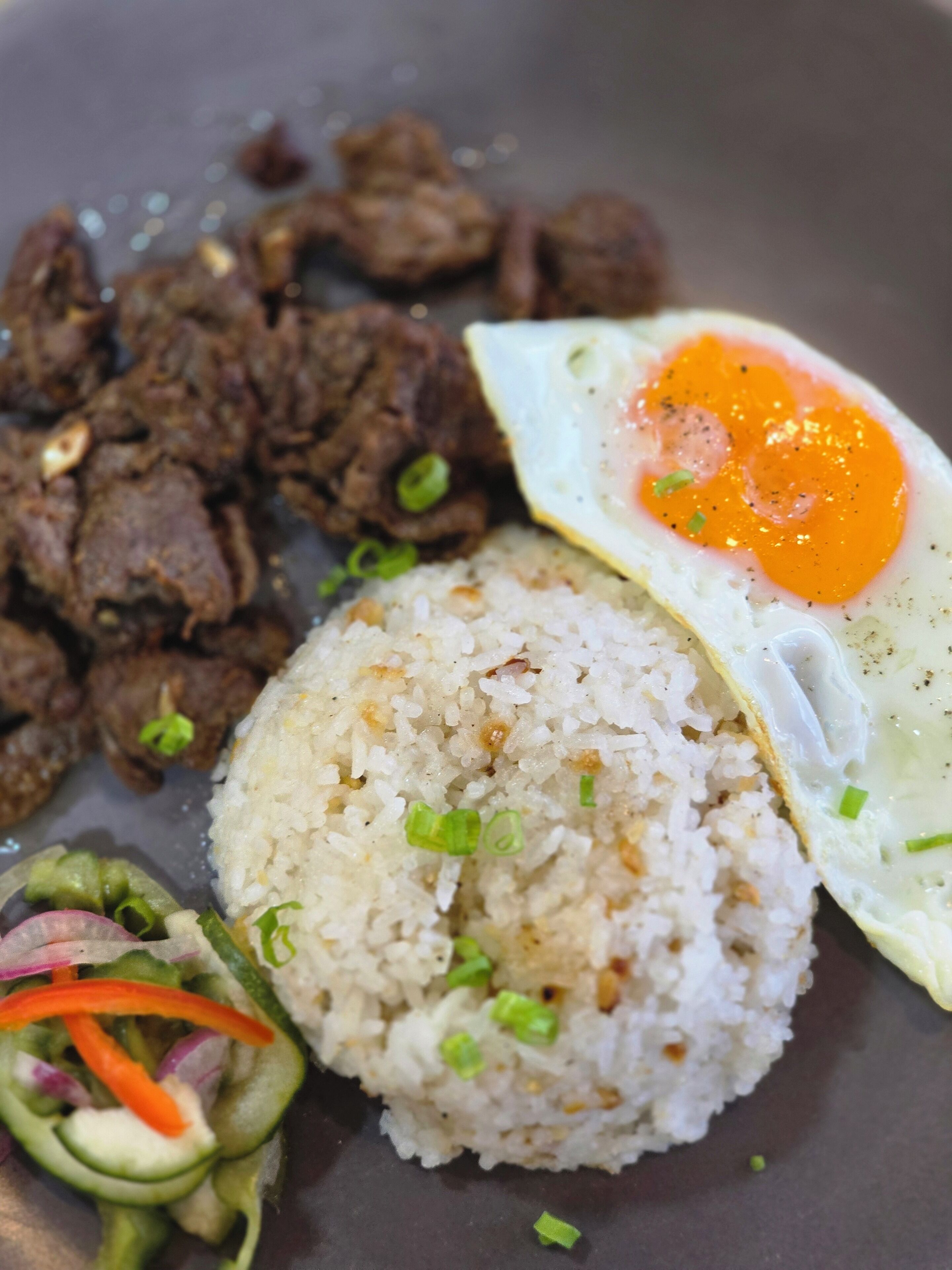 A plate of food with rice, beef, an egg, and a side salad.