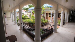 Un amplio atrium con columnas blancas, un jardín central y vistas al exterior.