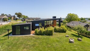 A modern house with a small detached garage, a well-maintained lawn, and a view of the surrounding neighborhood.