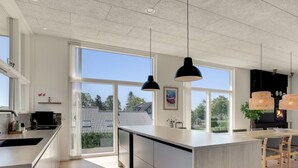 A modern kitchen with large windows, a central island, and pendant lighting.