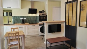 Una cocina compacta con comedor, lavadora y televisor fijado a la pared.