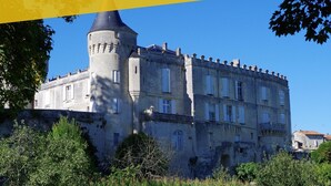 Un castillo histórico con una torre destacada, rodeado de abundante vegetación.