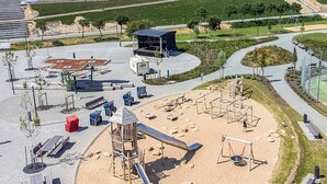 Un parque infantil con toboganes y columpios, una zona de estar techada y un área de juego con arena.