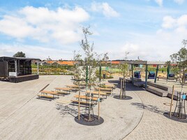 Un espacio al aire libre con mesas de picnic, un escenario y una zona de estar cubierta.