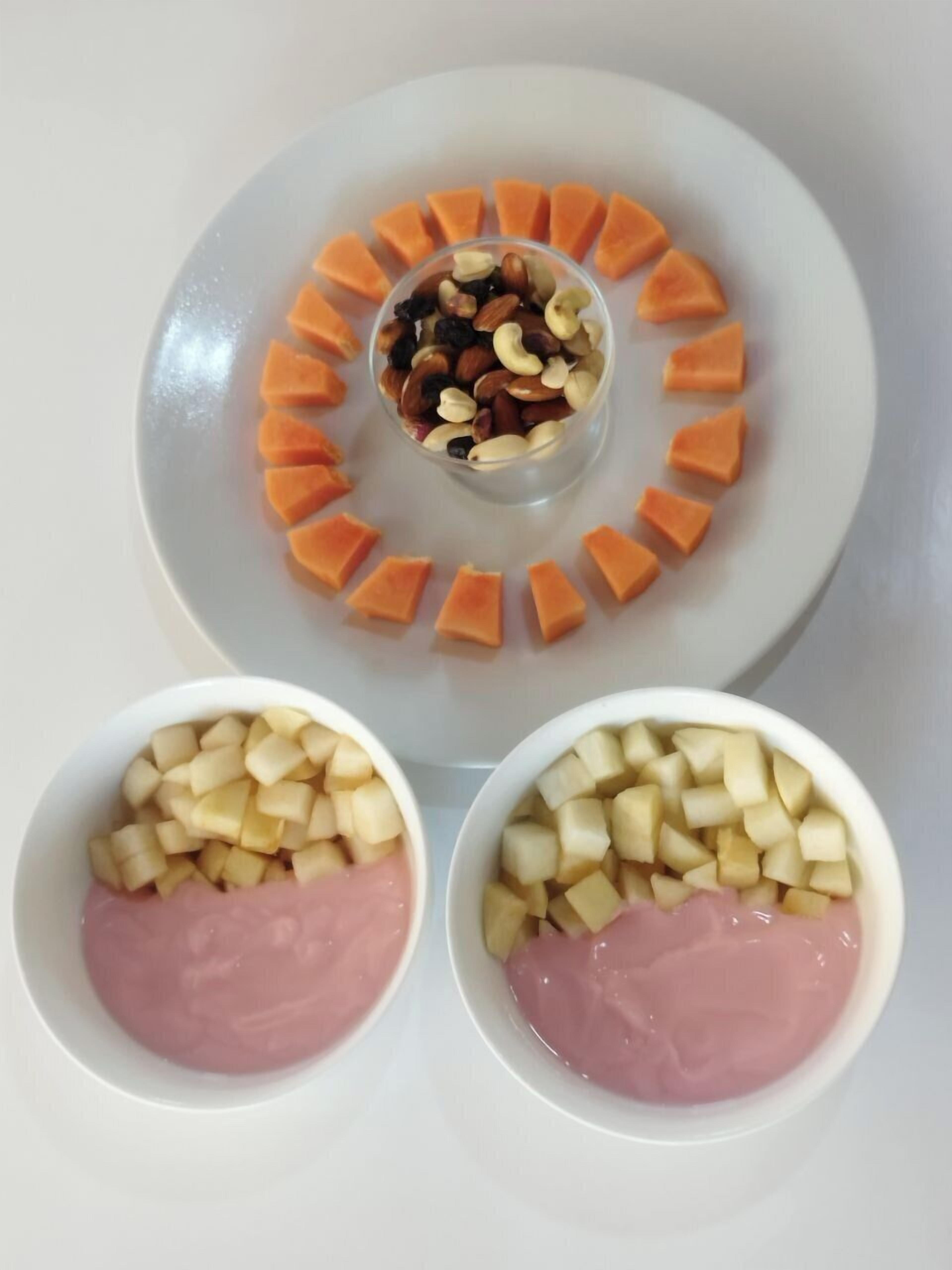 A white plate with a central bowl of mixed nuts and a ring of carrot slices, and two bowls of diced potatoes and ham.