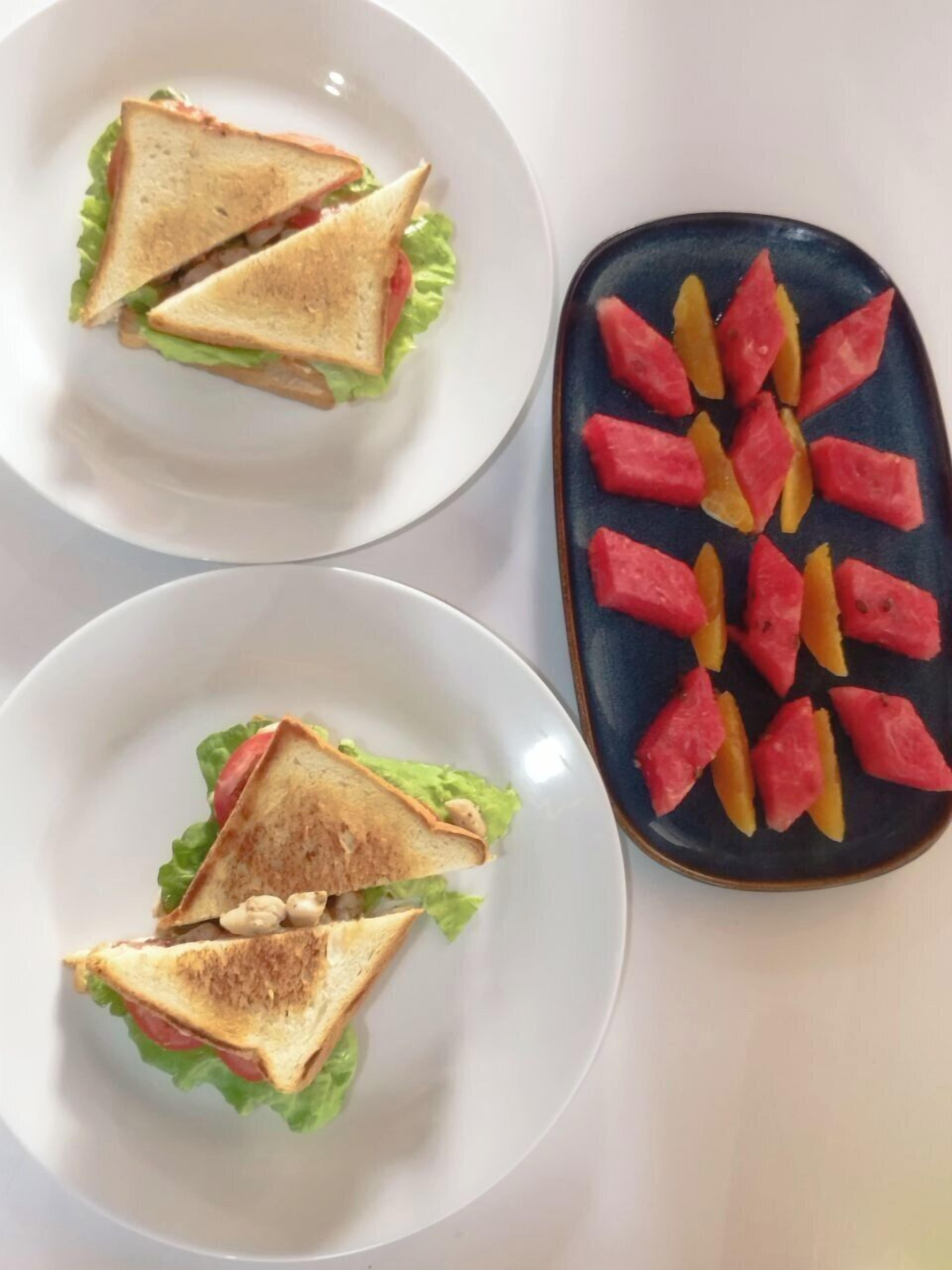 Two plates with sandwiches and a plate of watermelon slices.