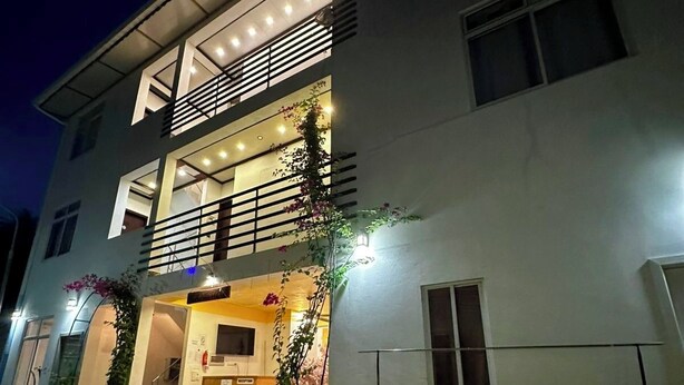 A two-story building with a reception area, a balcony, and potted plants.