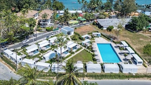 An aerial view of a coastal resort with multiple RVs, a swimming pool, and a view of the ocean. - Apple House (Choeng Thale)